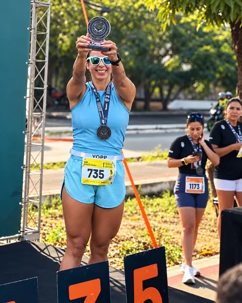 Atleta erguendo troféu no pódio