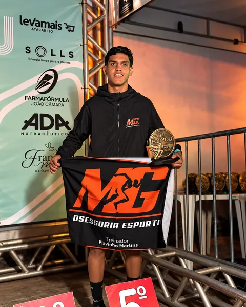 Jovem atleta com troféu e bandeira da MG
