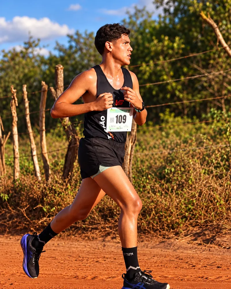 Jovem atleta correndo em estrada de terra vermelha