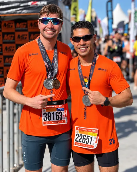 Dois atletas de laranja mostrando medalhas