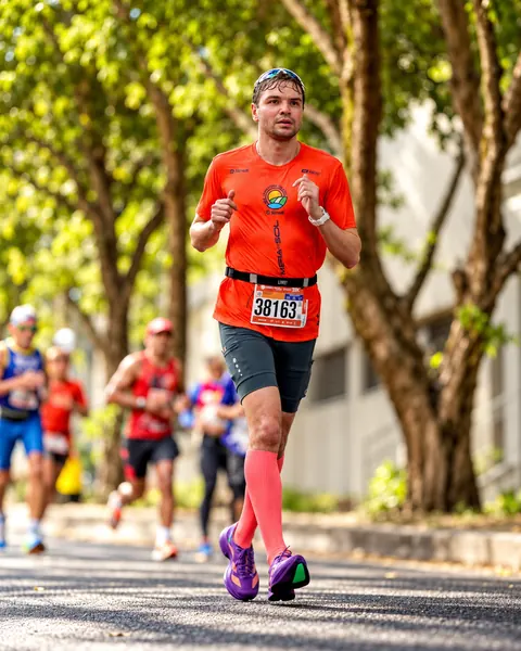 Atleta correndo em avenida arborizada