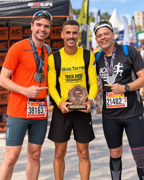 Três atletas com medalhas e troféu